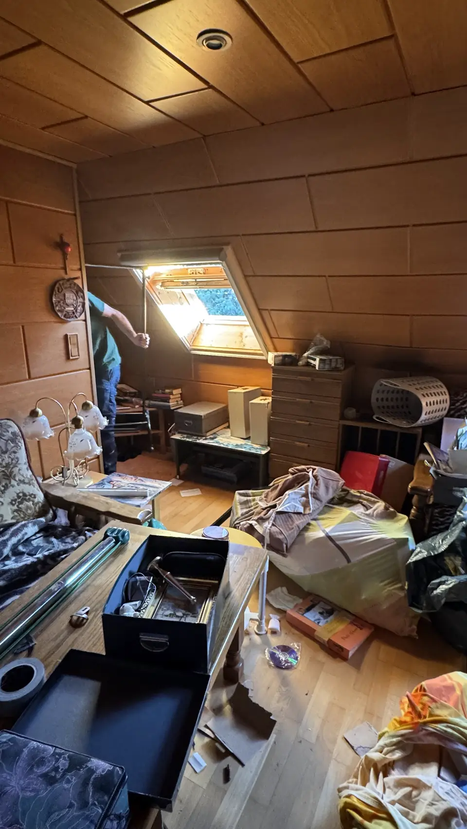 Dachzimmer mit Möbeln, Kisten und Säcken während der Räumung