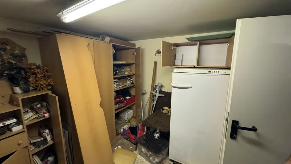 Kellerabteil mit Kasten, Kühlschrank und Krücken