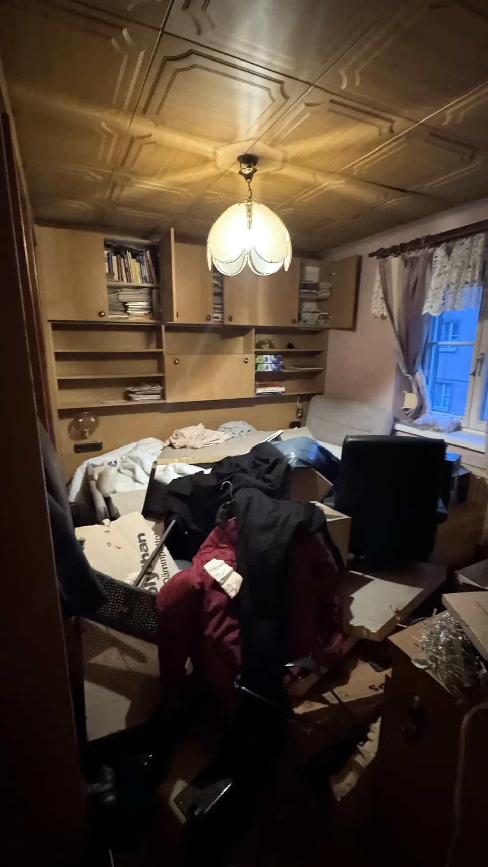 Schlafzimmer mit Holzdecke, Kleiderbergen und Kartons